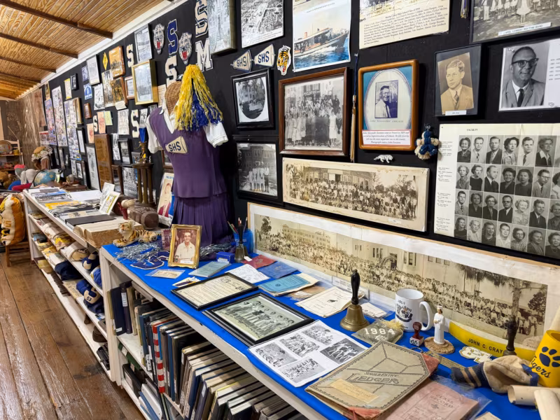 A wall of Martin County school photographs, letters and yearbooks above a table of school memorabilia and a cheerleader uniform
