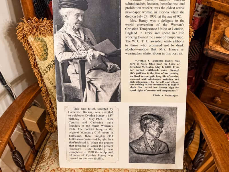 An upholstered rocking chair holding a framed photograph and story panel about Cynthia Burnette Haney